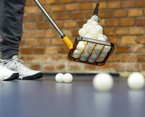 table tennis ball picker on the court with balls on the floor